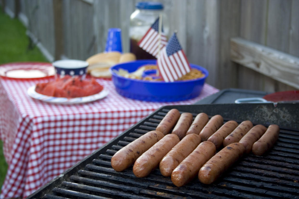 Hot dogs on the grill with a festive red-white-blue table in the background, complete with watermelon and a pot of sweet tea!  Nothing more American... Happy Independence Day!